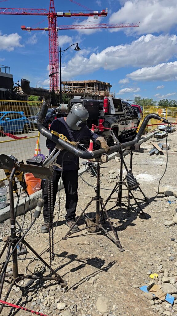 On-site pipe welding with construction cranes behind
